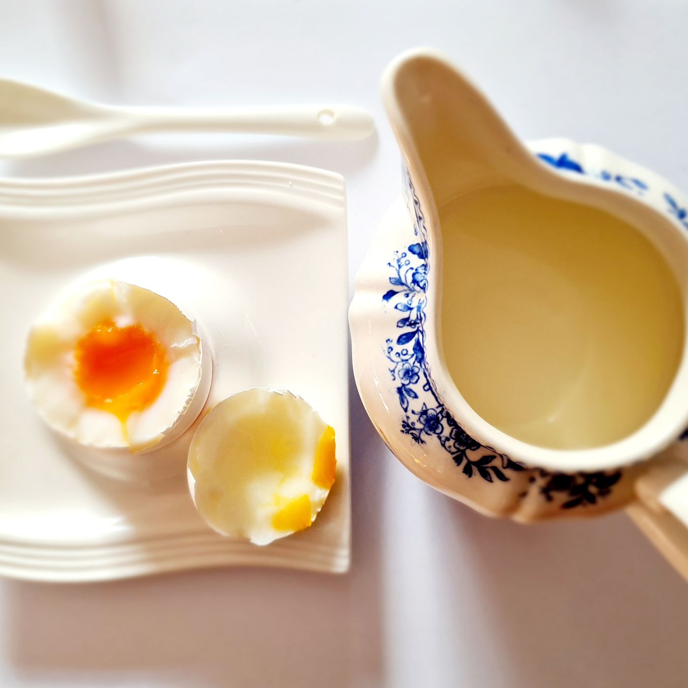 A ceramic gravy boat photographed close up beside an egg.